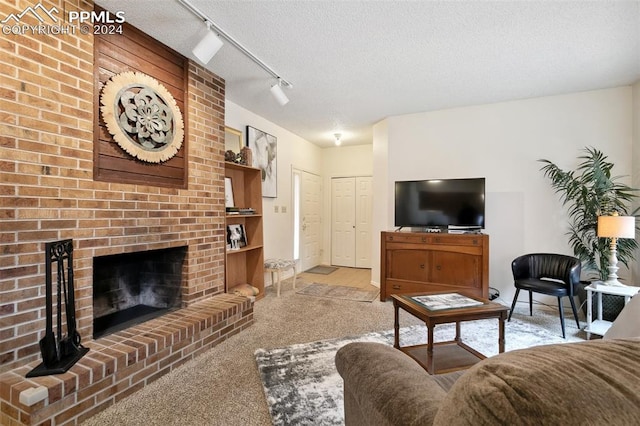 living room with light colored carpet, a textured ceiling, track lighting, and a fireplace