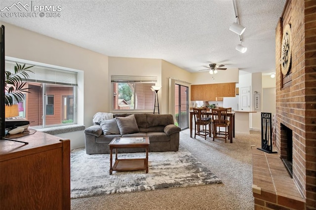 carpeted living room with ceiling fan, a textured ceiling, track lighting, and a fireplace