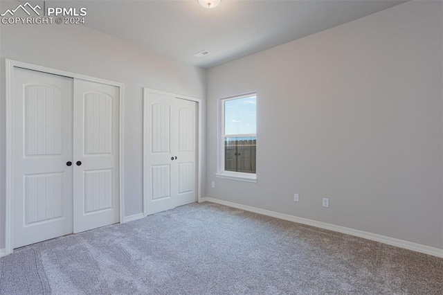 unfurnished bedroom with two closets and carpet floors