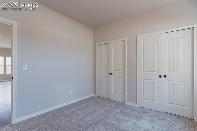 unfurnished bedroom with multiple closets and light colored carpet