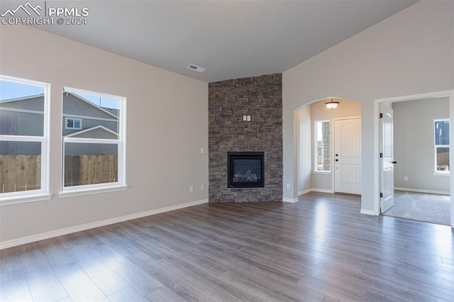 unfurnished living room featuring vaulted ceiling, wood-type flooring, and plenty of natural light