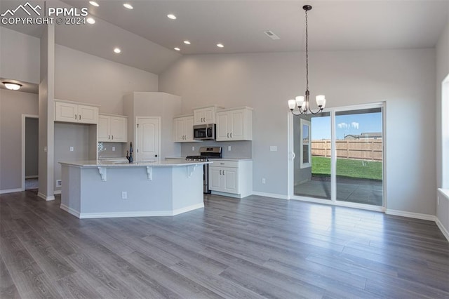 kitchen with a kitchen island with sink, white cabinets, stainless steel appliances, and high vaulted ceiling