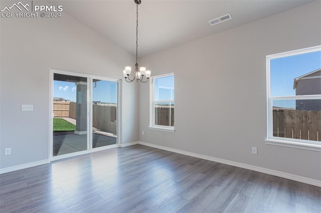 unfurnished room featuring dark hardwood / wood-style flooring, lofted ceiling, a chandelier, and a wealth of natural light