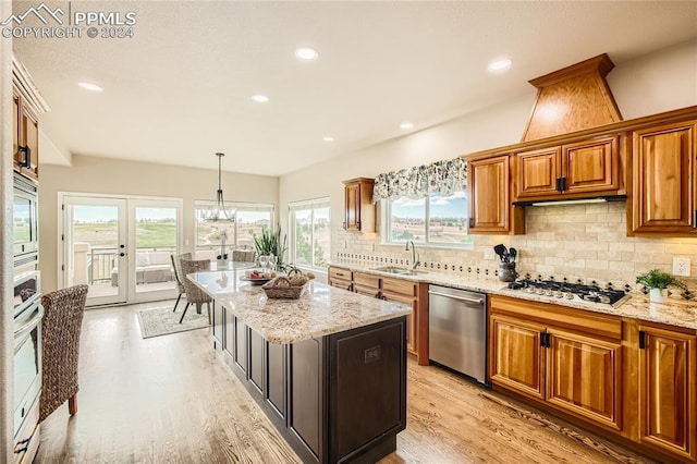 kitchen featuring a center island, appliances with stainless steel finishes, decorative light fixtures, and plenty of natural light