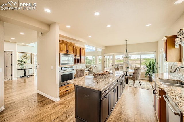 kitchen featuring sink, appliances with stainless steel finishes, light hardwood / wood-style flooring, and a center island