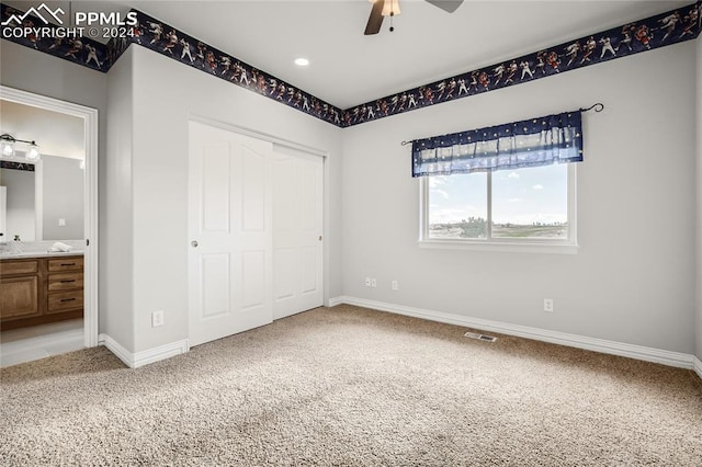 unfurnished bedroom featuring a closet, ensuite bath, carpet, and ceiling fan