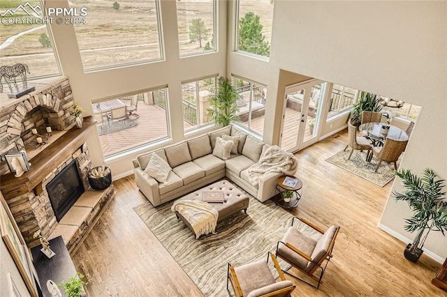 living room featuring a towering ceiling, a fireplace, and light wood-type flooring