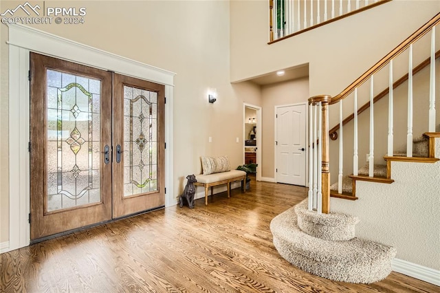 foyer featuring french doors, hardwood / wood-style flooring, and a high ceiling