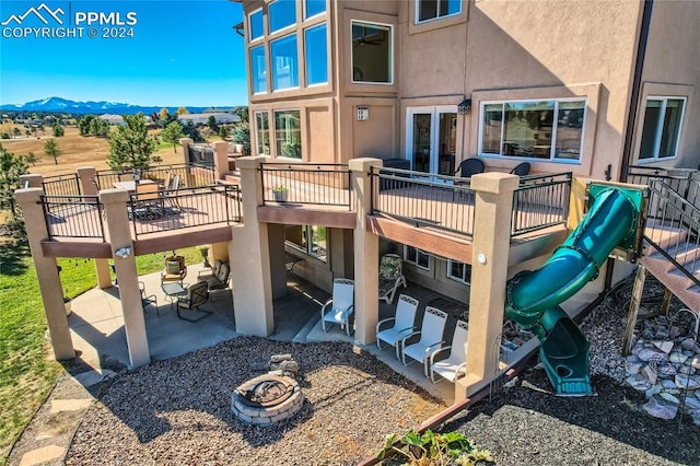 view of jungle gym with an outdoor fire pit, a patio, and a deck with mountain view