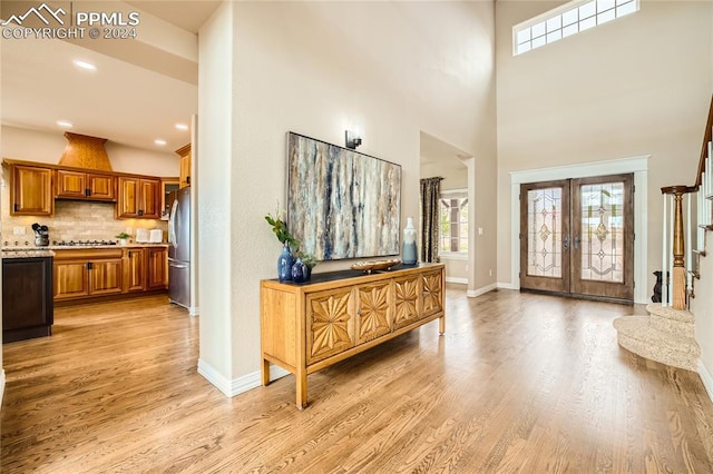 entrance foyer featuring french doors, a towering ceiling, and light hardwood / wood-style flooring