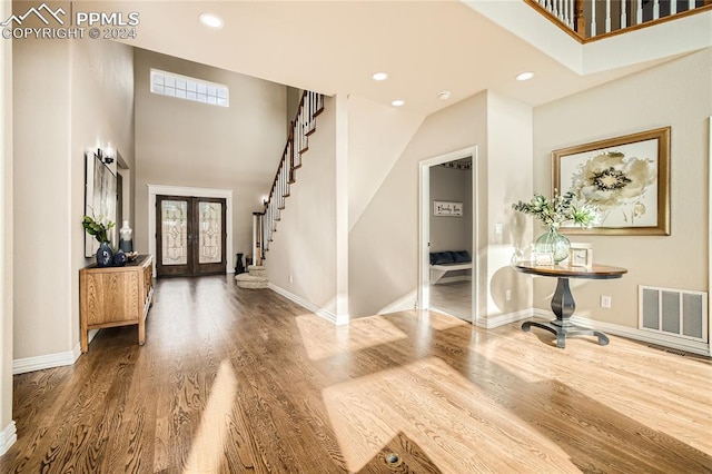 entryway featuring french doors, hardwood / wood-style floors, and a high ceiling