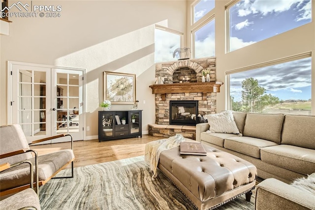 living room featuring a high ceiling, a stone fireplace, and light hardwood / wood-style floors