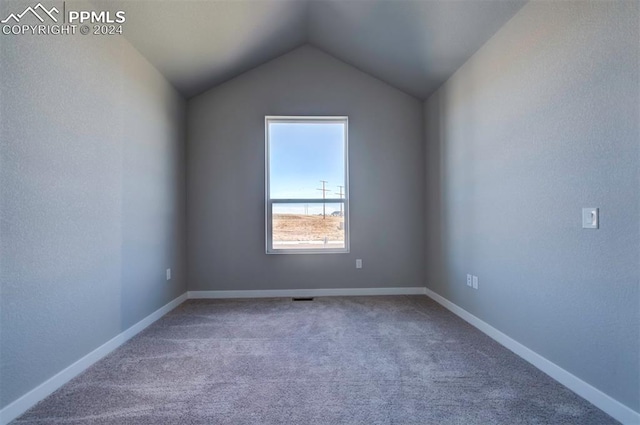 carpeted spare room featuring lofted ceiling