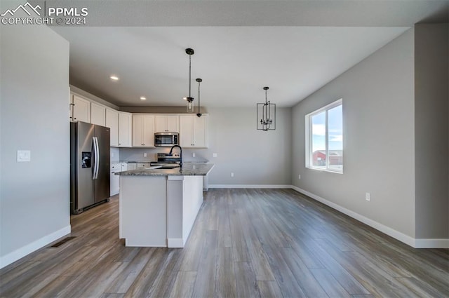 kitchen with light hardwood / wood-style floors, stainless steel appliances, white cabinets, light stone counters, and a kitchen island with sink