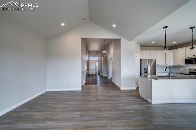 kitchen with dark hardwood / wood-style floors, hanging light fixtures, stainless steel appliances, vaulted ceiling, and white cabinetry