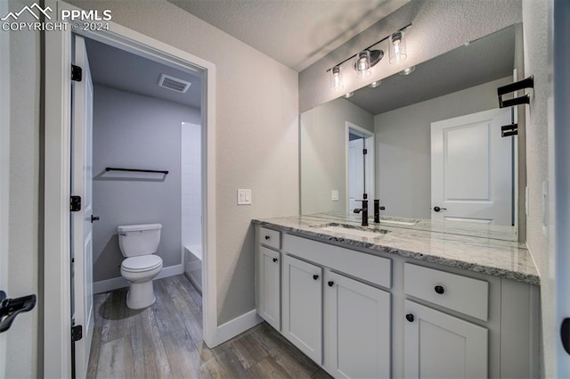 full bathroom with hardwood / wood-style floors, a textured ceiling, toilet, shower / bathtub combination, and vanity