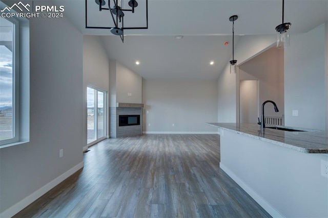 kitchen featuring hanging light fixtures, sink, light stone countertops, high vaulted ceiling, and dark hardwood / wood-style flooring