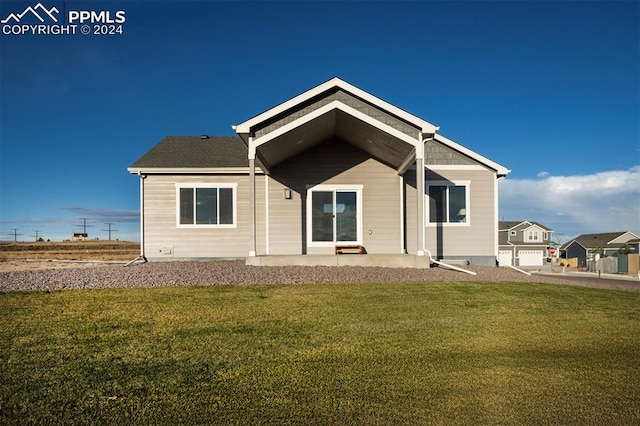 rear view of property with a garage and a lawn