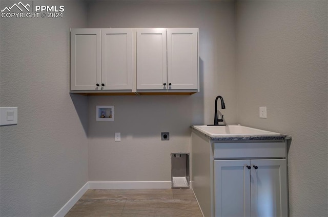 washroom featuring hookup for a washing machine, sink, electric dryer hookup, cabinets, and light hardwood / wood-style flooring