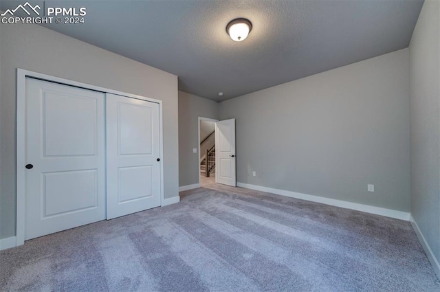 unfurnished bedroom featuring a closet, carpet, and a textured ceiling