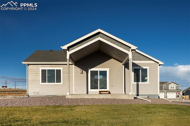 rear view of house featuring a lawn and a garage