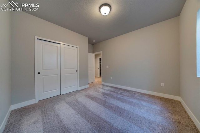 unfurnished bedroom featuring a closet, a textured ceiling, and carpet floors