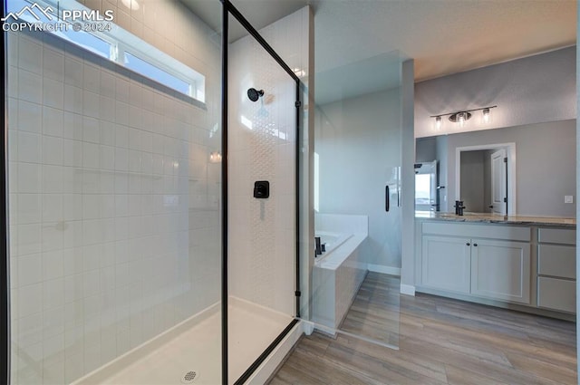 bathroom with vanity, independent shower and bath, and wood-type flooring