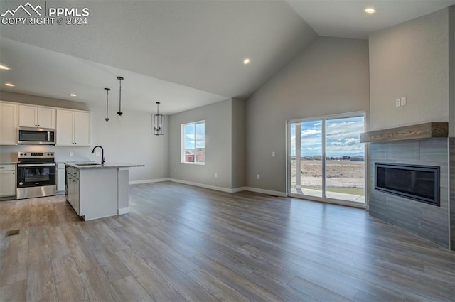 kitchen featuring light hardwood / wood-style flooring, stainless steel appliances, a center island with sink, sink, and white cabinets