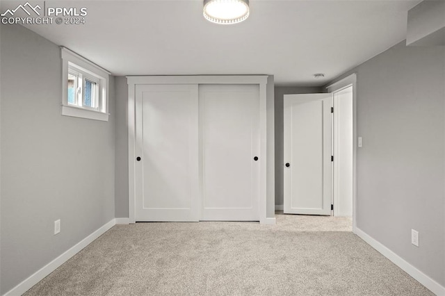 unfurnished bedroom with light colored carpet and a closet