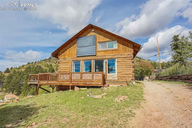 rear view of property featuring a deck and a lawn