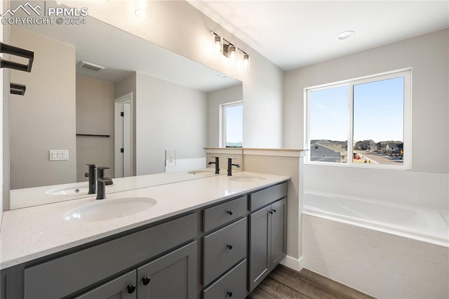 bathroom with tiled tub, vanity, and hardwood / wood-style flooring