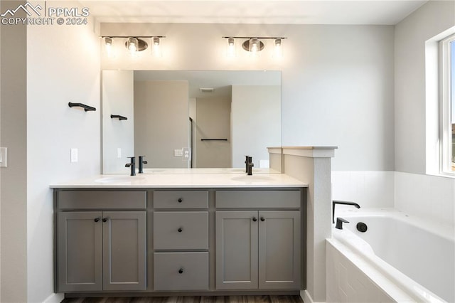 bathroom featuring hardwood / wood-style floors, vanity, and tiled tub