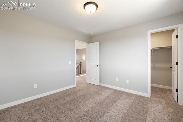 unfurnished bedroom with carpet, a spacious closet, and a closet