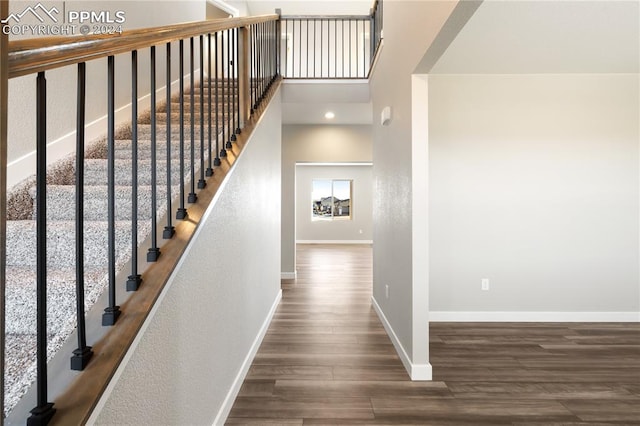 stairs featuring hardwood / wood-style floors and a high ceiling