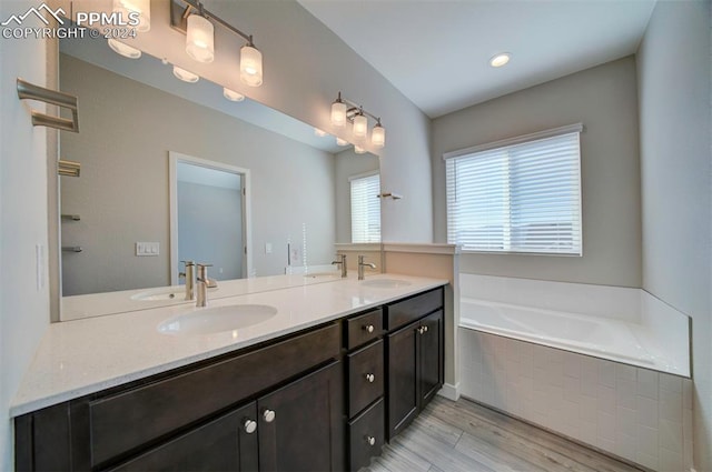 bathroom featuring vanity, wood-type flooring, and tiled bath