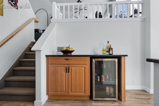 bar with light hardwood / wood-style floors and beverage cooler