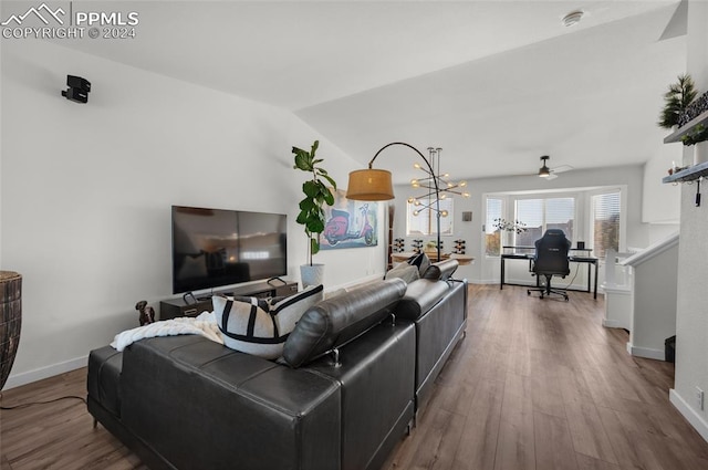 living room with hardwood / wood-style flooring, ceiling fan with notable chandelier, and vaulted ceiling