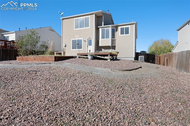 rear view of property with a wooden deck and cooling unit