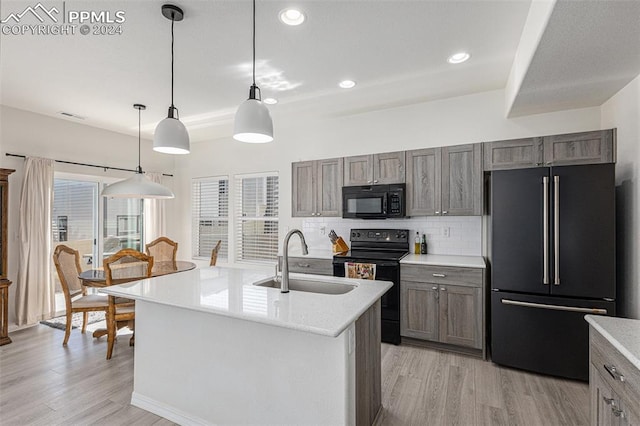 kitchen featuring black appliances, sink, light wood-type flooring, and hanging light fixtures