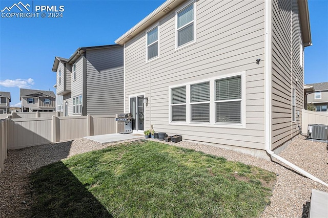 rear view of house featuring a patio, a yard, and central AC unit