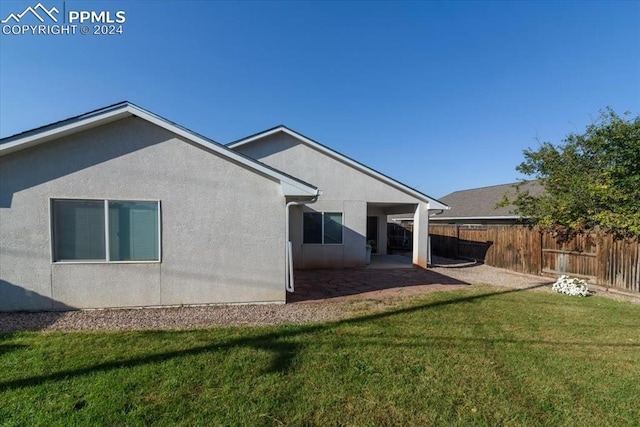 back of house with a patio and a lawn