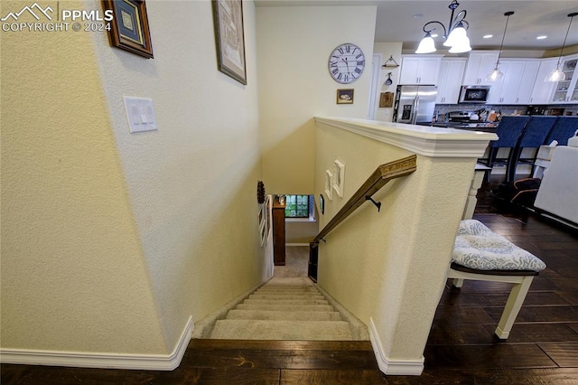 staircase with a notable chandelier and wood-type flooring