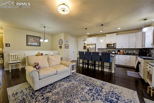 living room featuring a notable chandelier, sink, and dark wood-type flooring