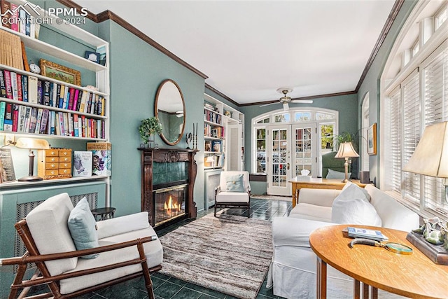 living area featuring ceiling fan, dark tile patterned floors, ornamental molding, and a tile fireplace