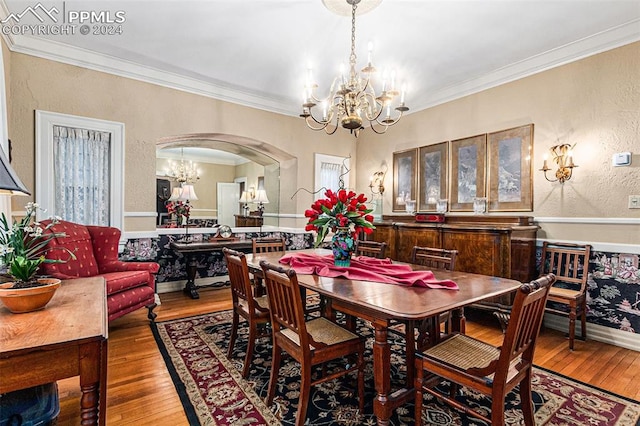 dining space featuring hardwood / wood-style floors, crown molding, and an inviting chandelier