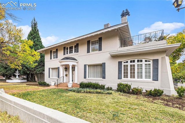 view of front of property featuring a balcony and a front lawn