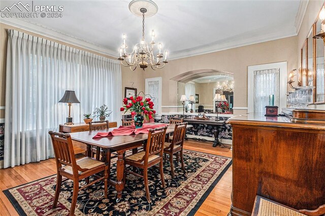 dining room featuring light hardwood / wood-style floors, ornamental molding, and an inviting chandelier