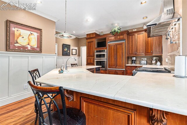 kitchen with sink, hanging light fixtures, light hardwood / wood-style flooring, crown molding, and range