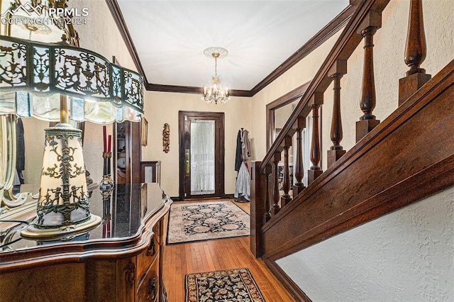 foyer featuring hardwood / wood-style floors, a notable chandelier, and crown molding