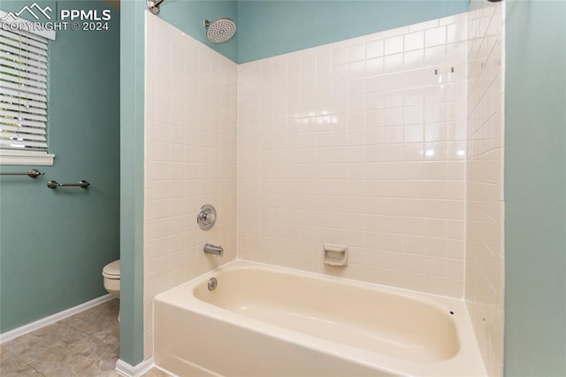 bathroom with toilet, tile patterned flooring, and tiled shower / bath